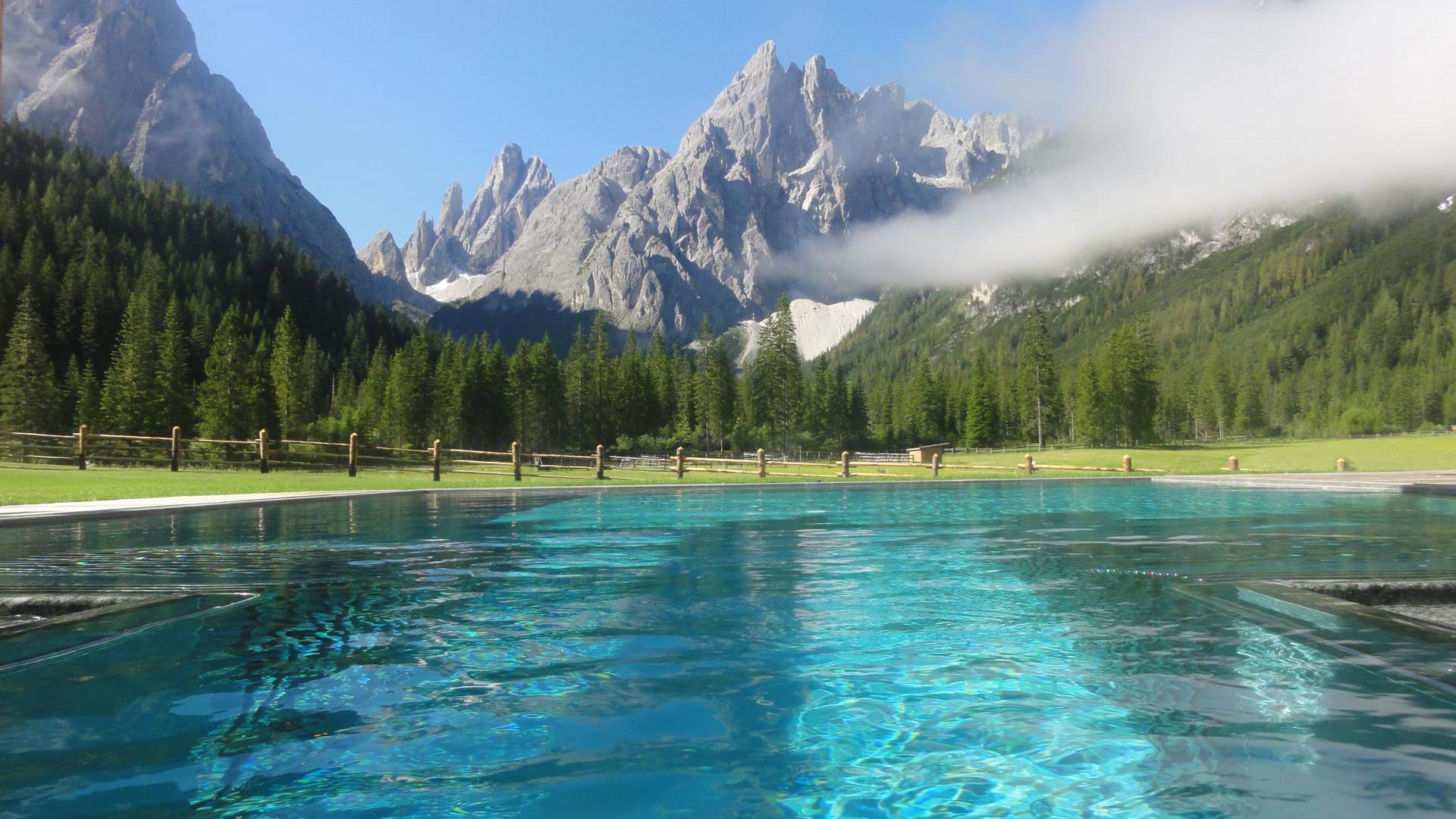 The outdoor pool with a view on the Dolomites in summer